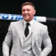 Conor McGregor smiles in the octagon in a grey suit