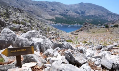 PA Media A direction sign on a rocky path in the hills of Pedi (Pedi centre pictured in the distance, right), a small fishing village in Symi, Greece, pointing toward Agia Marina on 8 June