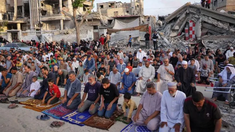 Getty Images People performing Eid prayers outdoors surrounded by rubble